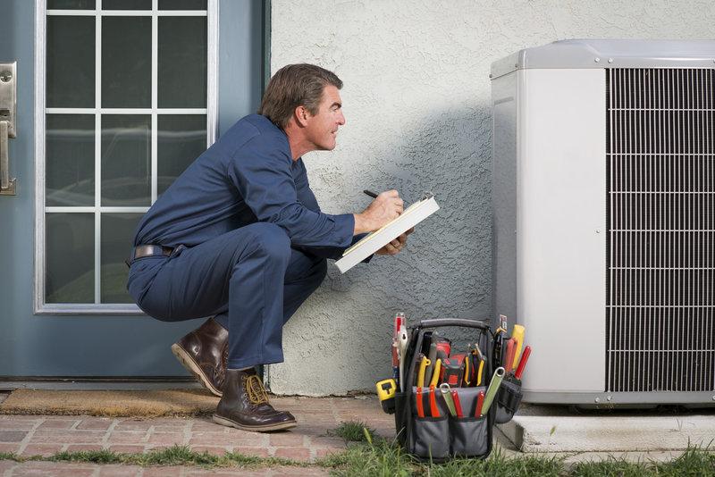 HVAC technician evaluating an air conditioner for repairs